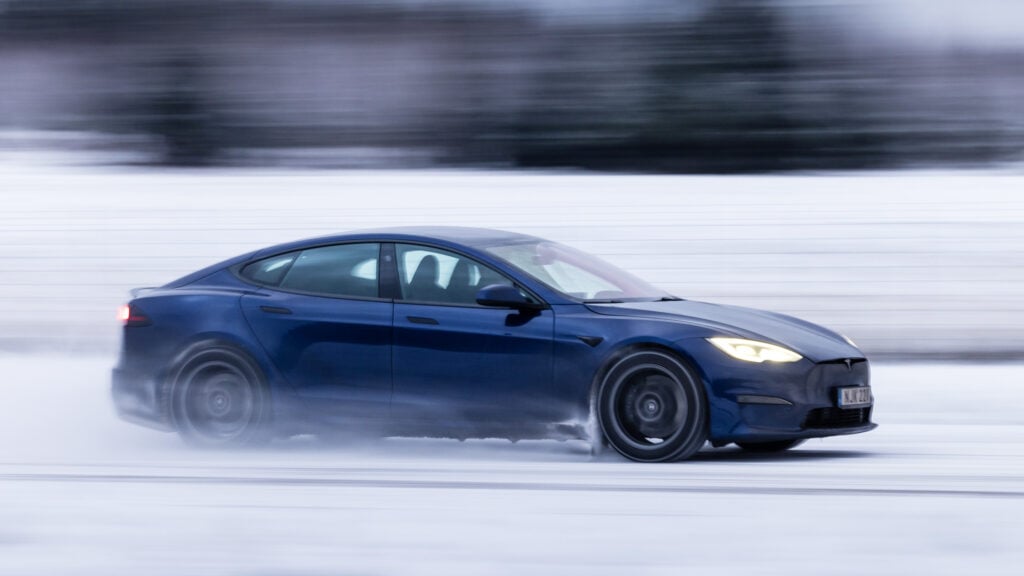 Blå Tesla Model S Plaid kör på snöbelaggd väg.