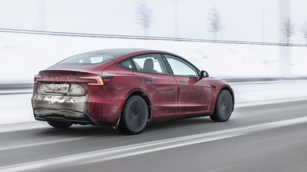 Tesla Model 3 facelift snett bakifrån på vinterväg.