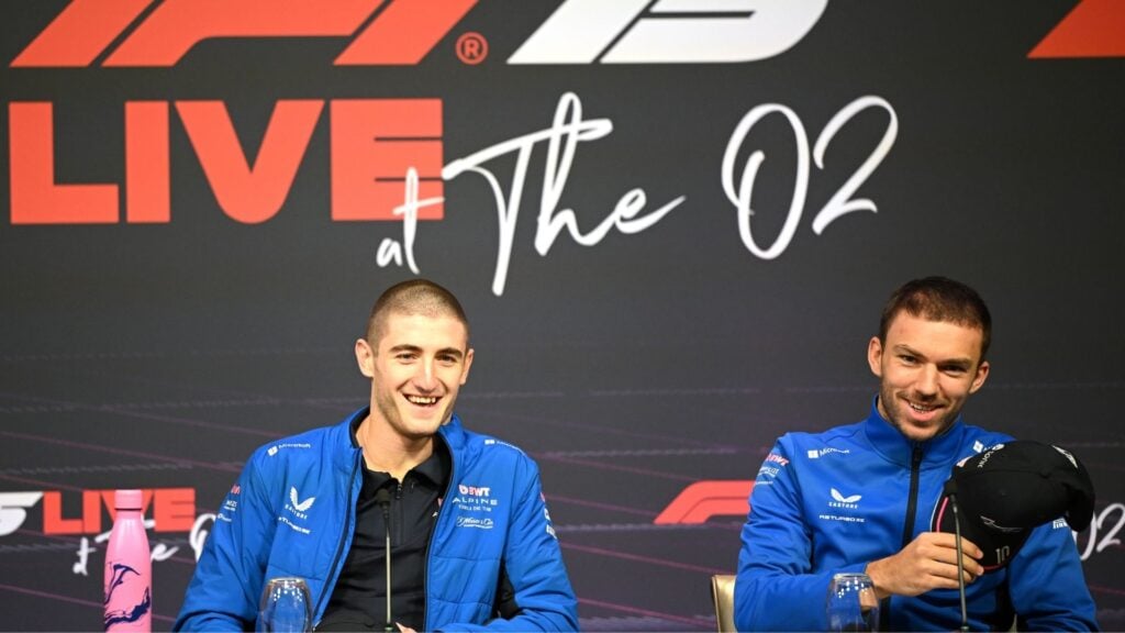 Jack Doohan och Pierre Gasly från Alpine F1 Team sitter vid en presskonferens under F1 Live at The O2 i London, båda med kortsnaggade frisyrer och blå Alpine-jackor.