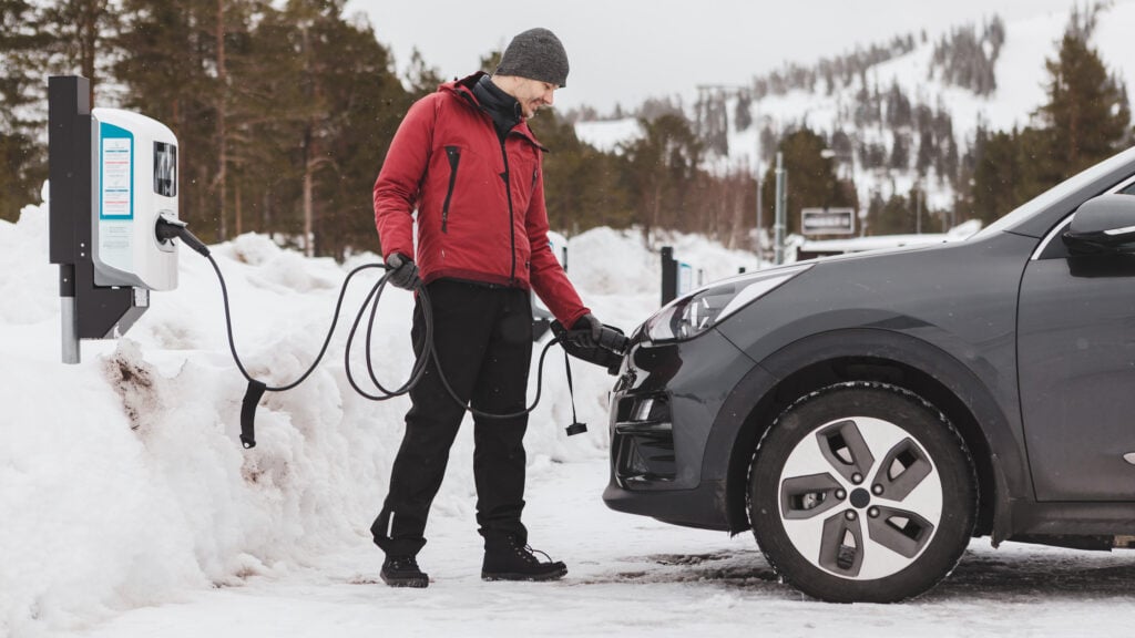 Laddning av elbil på snöbelaggd parkering.