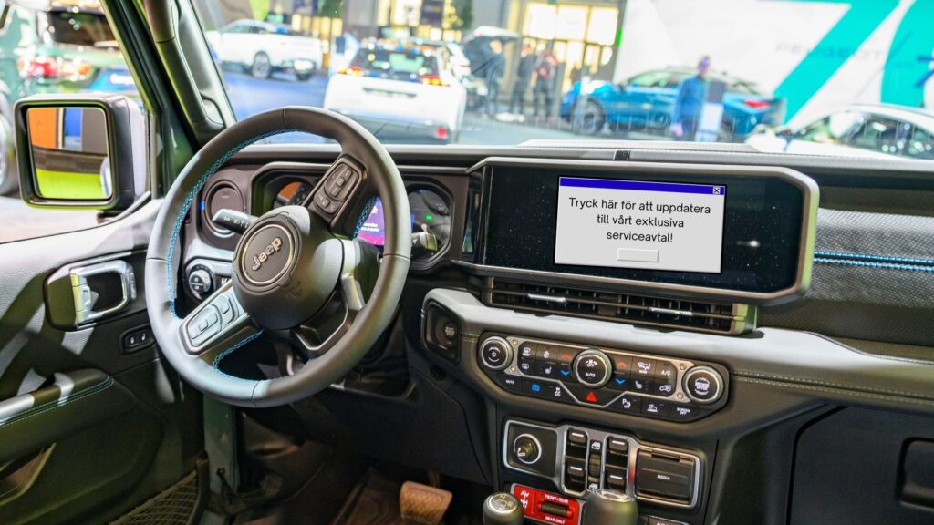 Jeep-interiör med en infotainmentskärm som visar ett popup-fönster med texten: ‘Tryck här för att uppdatera till vårt exklusiva serviceavtal!’