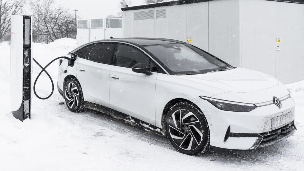 Vit Volkswagen ID. 7 laddar på Tesla Supercharger IV i snöigt vinterväder.