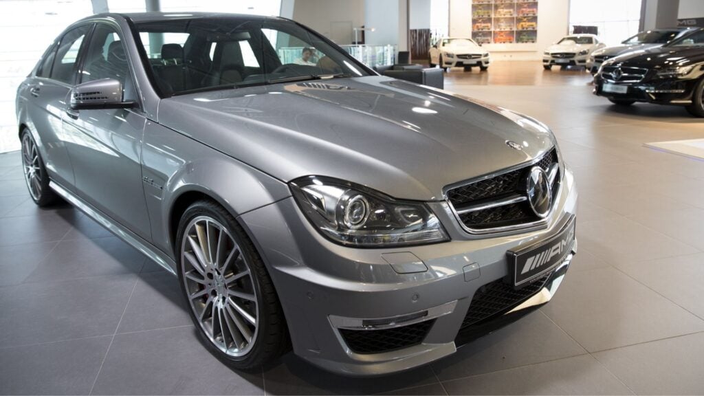En silverfärgad Mercedes-AMG C63 i en bilhall, en modell som tidigare var känd för sin kraftfulla V8-motor.