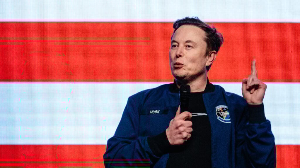 Elon Musk på scen framför en LED-skärm som visar en amerikansk flagga.
