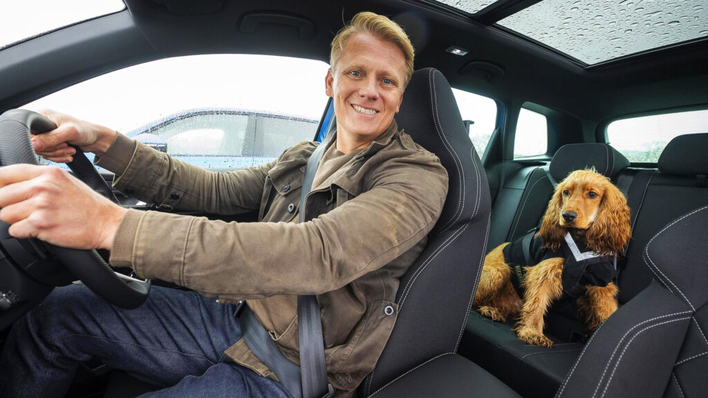 Veterinären Scott Miller med sin hund Mango i sele i baksätet.