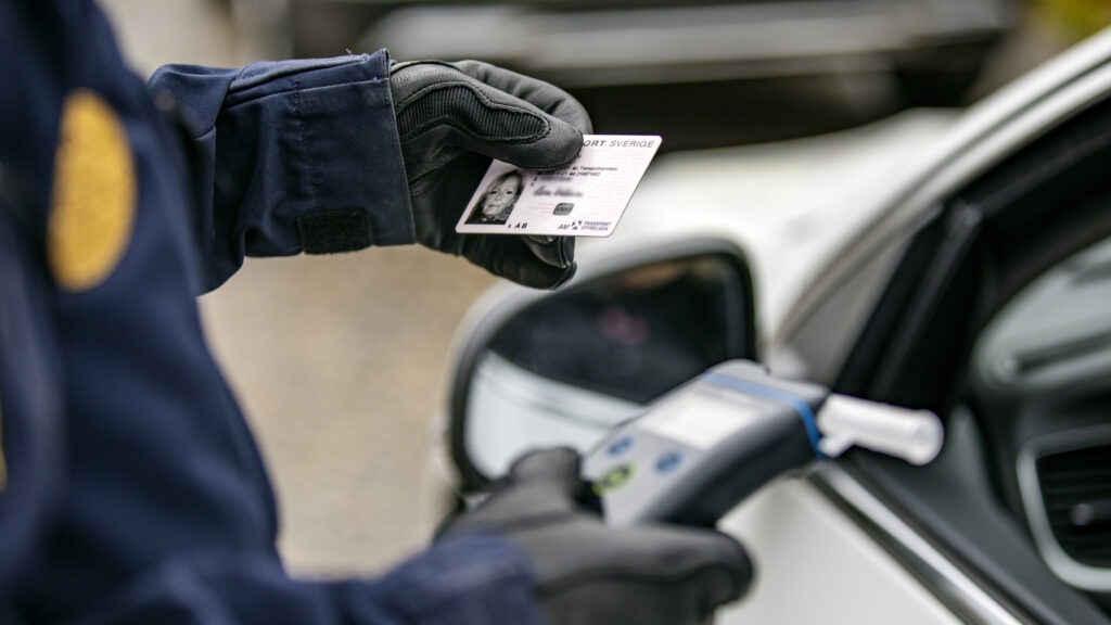 En polis placerar en parkeringsborg på en bil. (AI text)