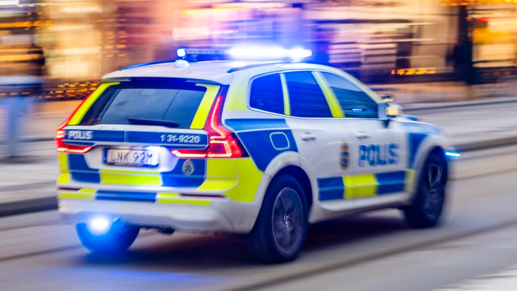 Polisbil på utryckning med blinkande ljus.