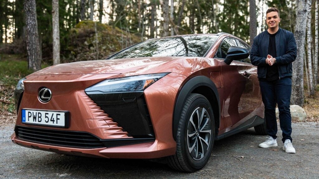 Lexus RZ 300e i färgen Sonic Copper parkerad i skogsmiljö tillsammans med provförare.