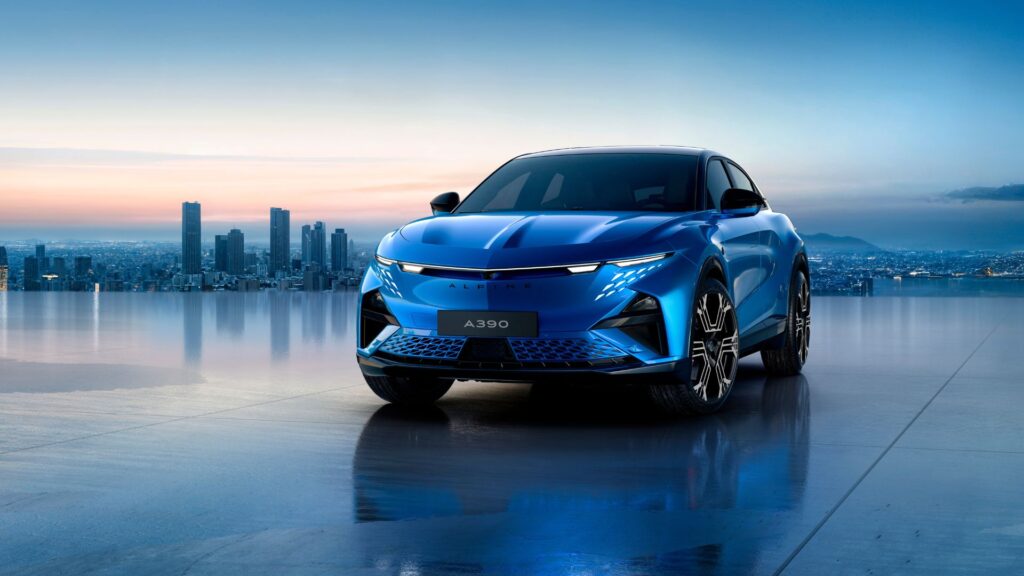 Alpine A390 eldriven SUV i blått med stad i bakgrunden, sedd snett framifrån.