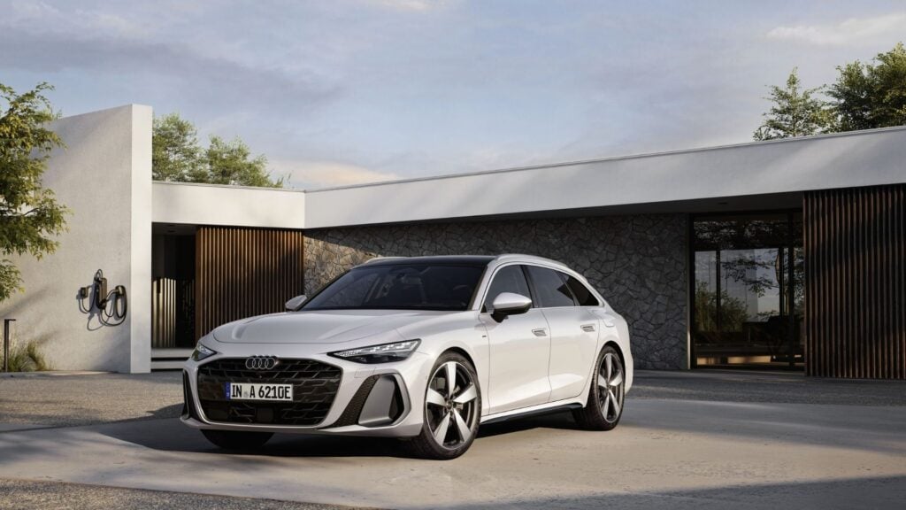 Audi A6 Avant e-hybrid 2025 i vitt – sedd snett framifrån parkerad framför modern villa.