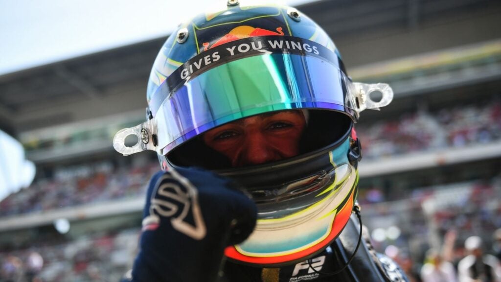 Svensk-brittiske racingföraren Arvid Lindblad i Red Bull-hjälm med visiret nedfällt, gör en segervink i depån – aktuell för debut i Formel 1 under 2025.