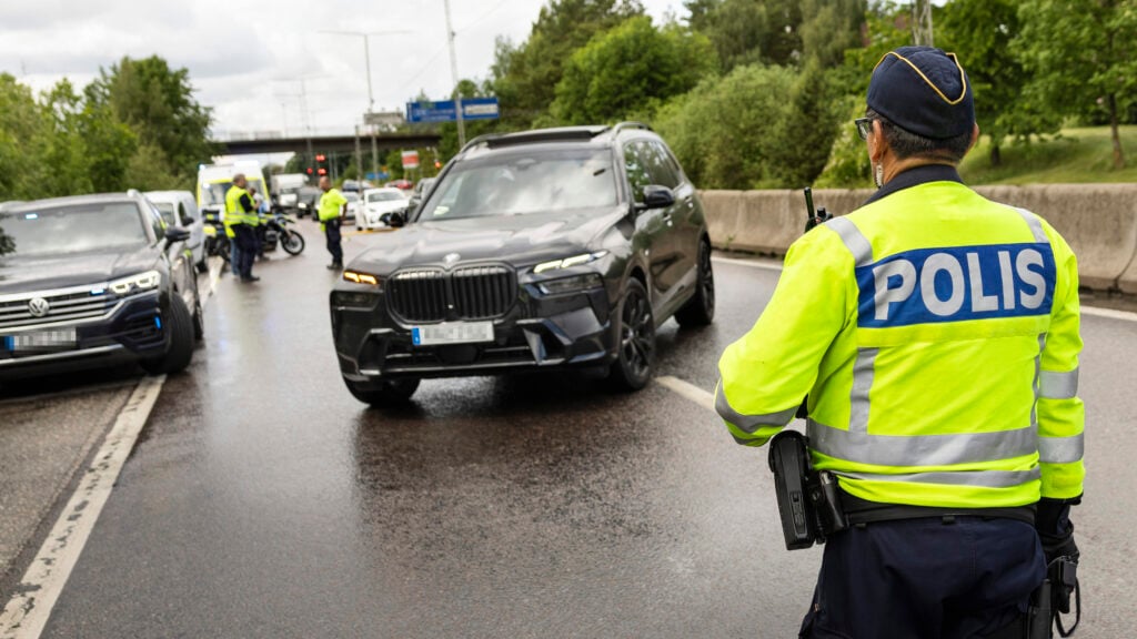 Trafikpolis stoppar stor svart BMW X5 vid en poliskontroll.