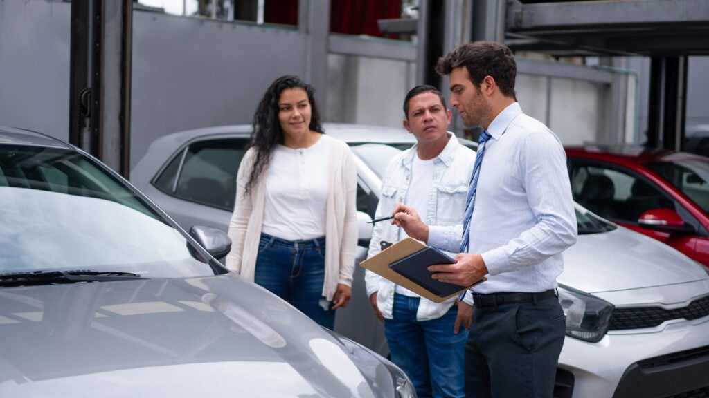 Bilförsäljare visar bil för ett par.