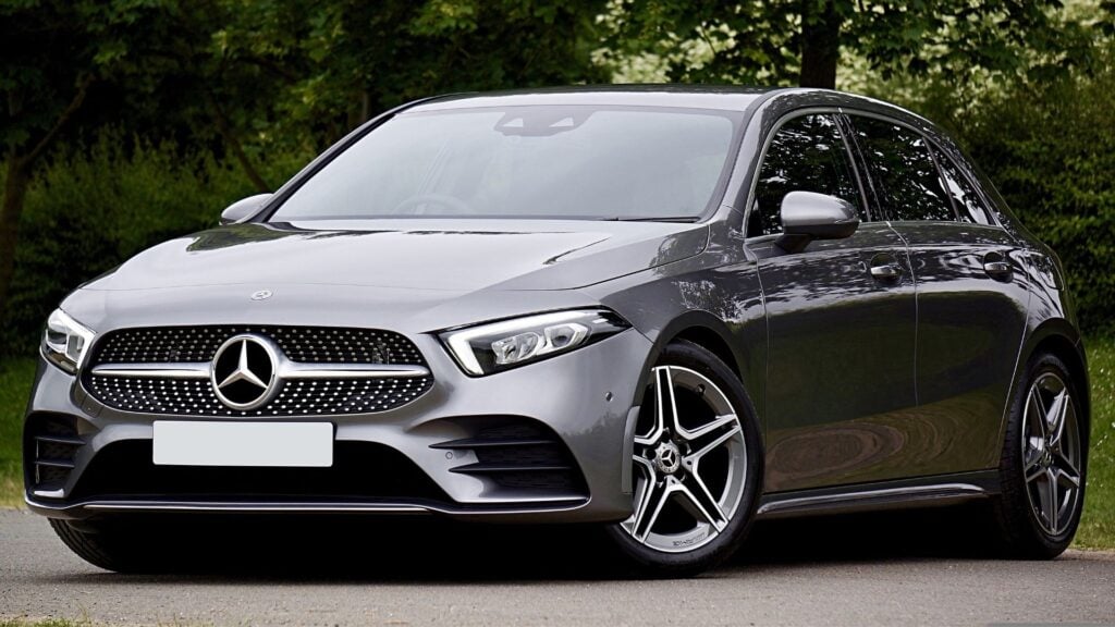 Grå Mercedes A-Klass hatchback av tidigare årsmodell, parkerad i grönskande miljö.