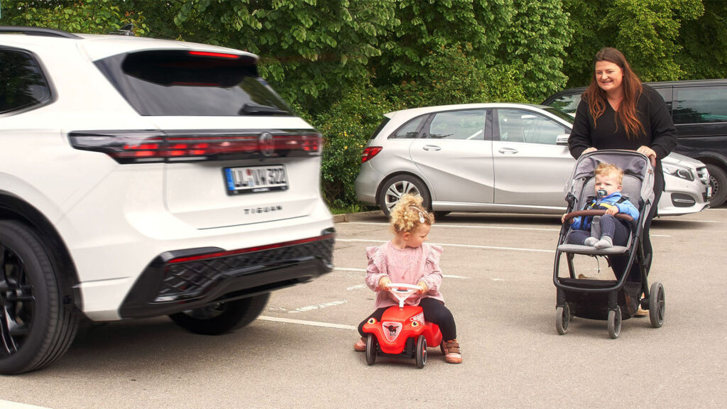 Barn som kör trambil bakom parkerad SUV.
