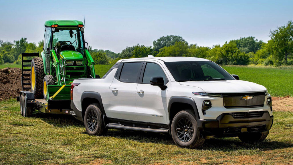 Vit Chevrolet Silverado EV Max Range med liten traktor på släp.