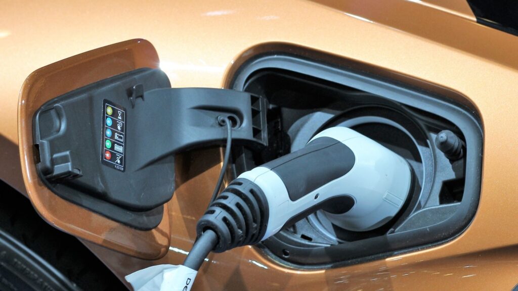 Närbild på elbil som laddas via kabel.