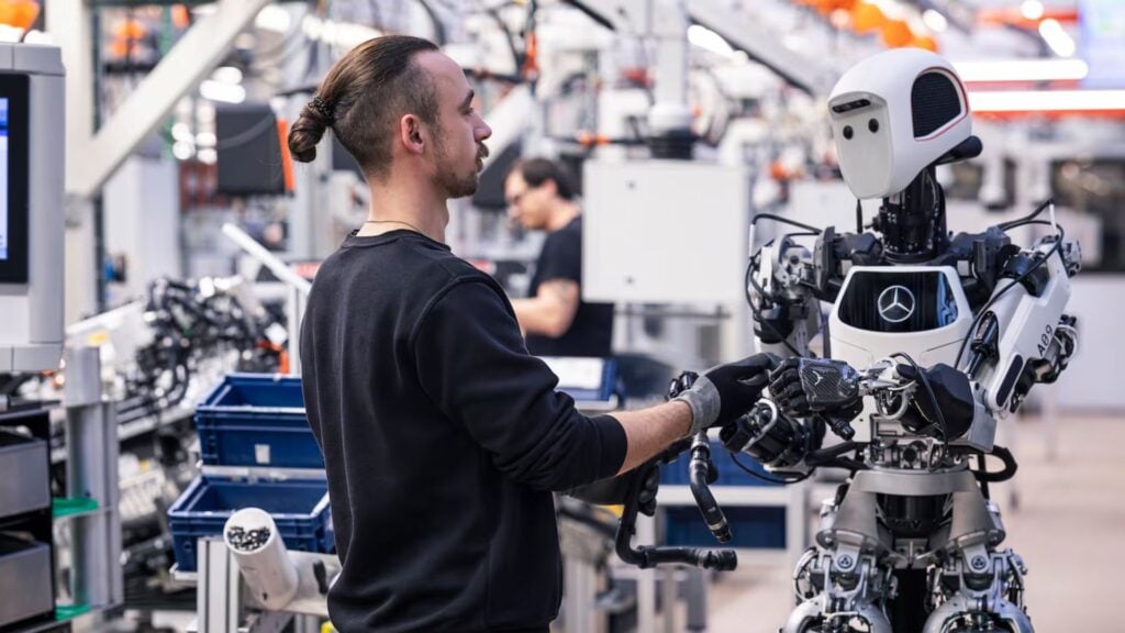 Mercedes-anställd samarbetar med humanoid robot i bilfabrik
