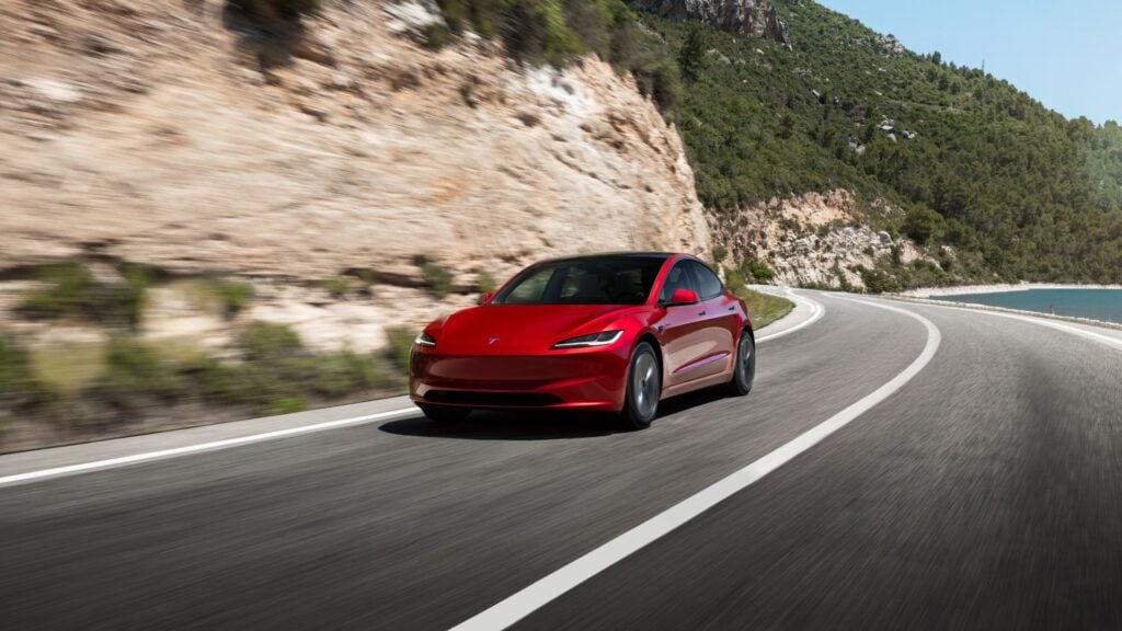 Röd Tesla Model 3 vid körning på landsväg i Sverige