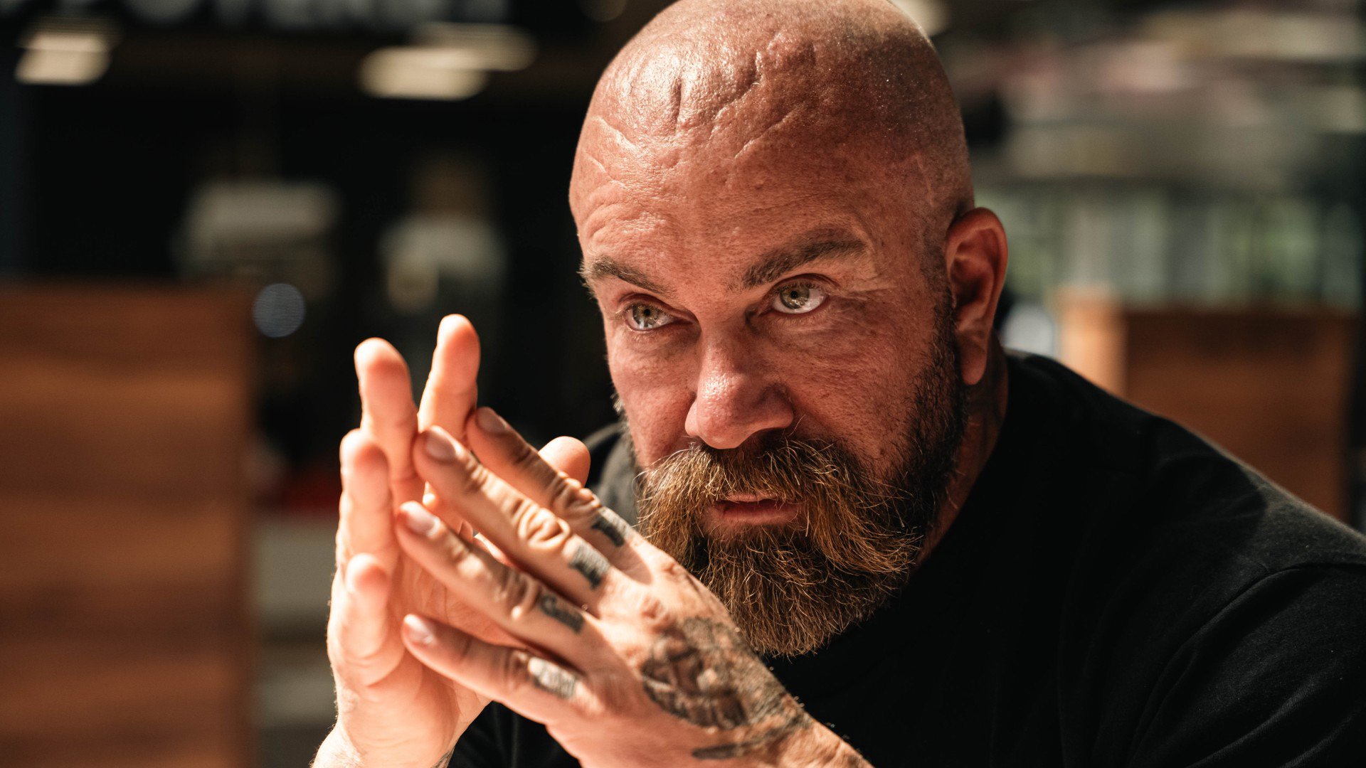 Jan Emanuel sitter med knäppta händer och ser sammanbiten ut.