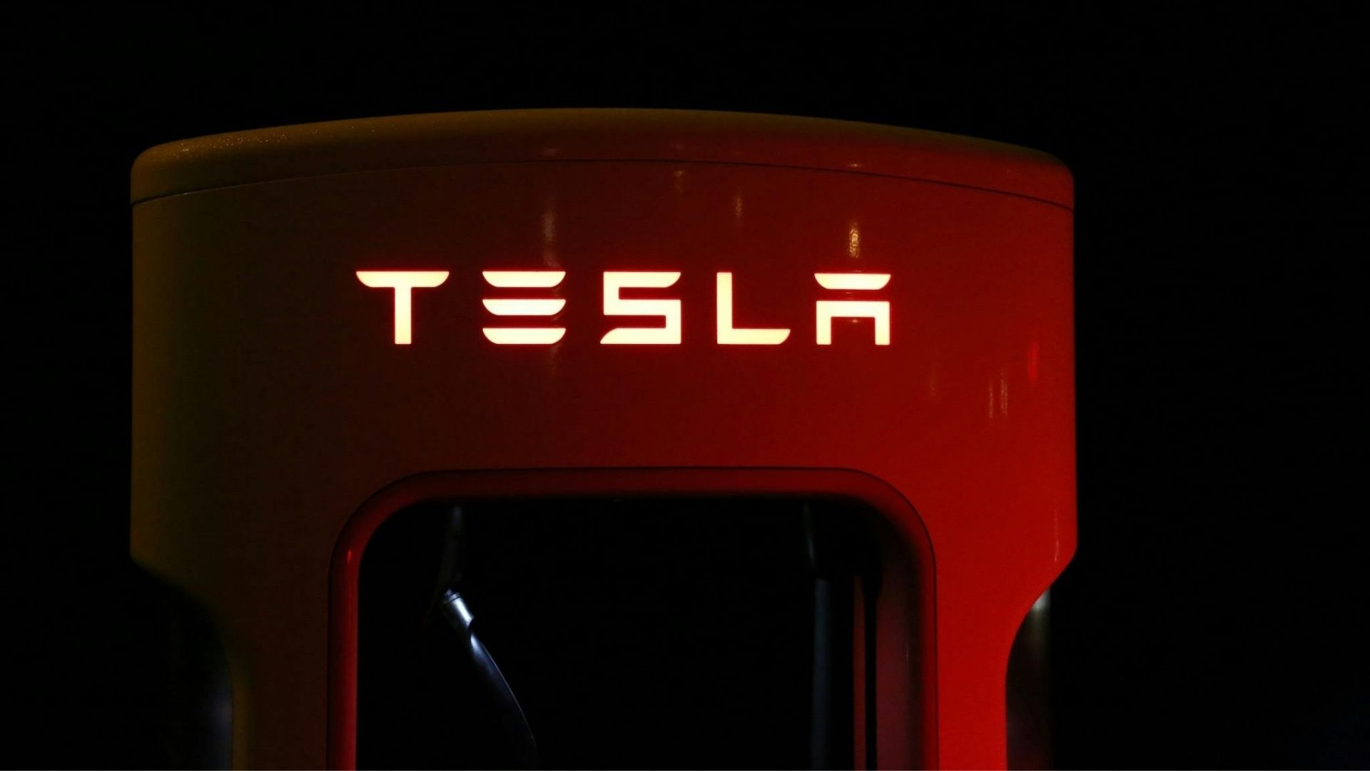 Tesla-logotyp på en laddstation i mörker.