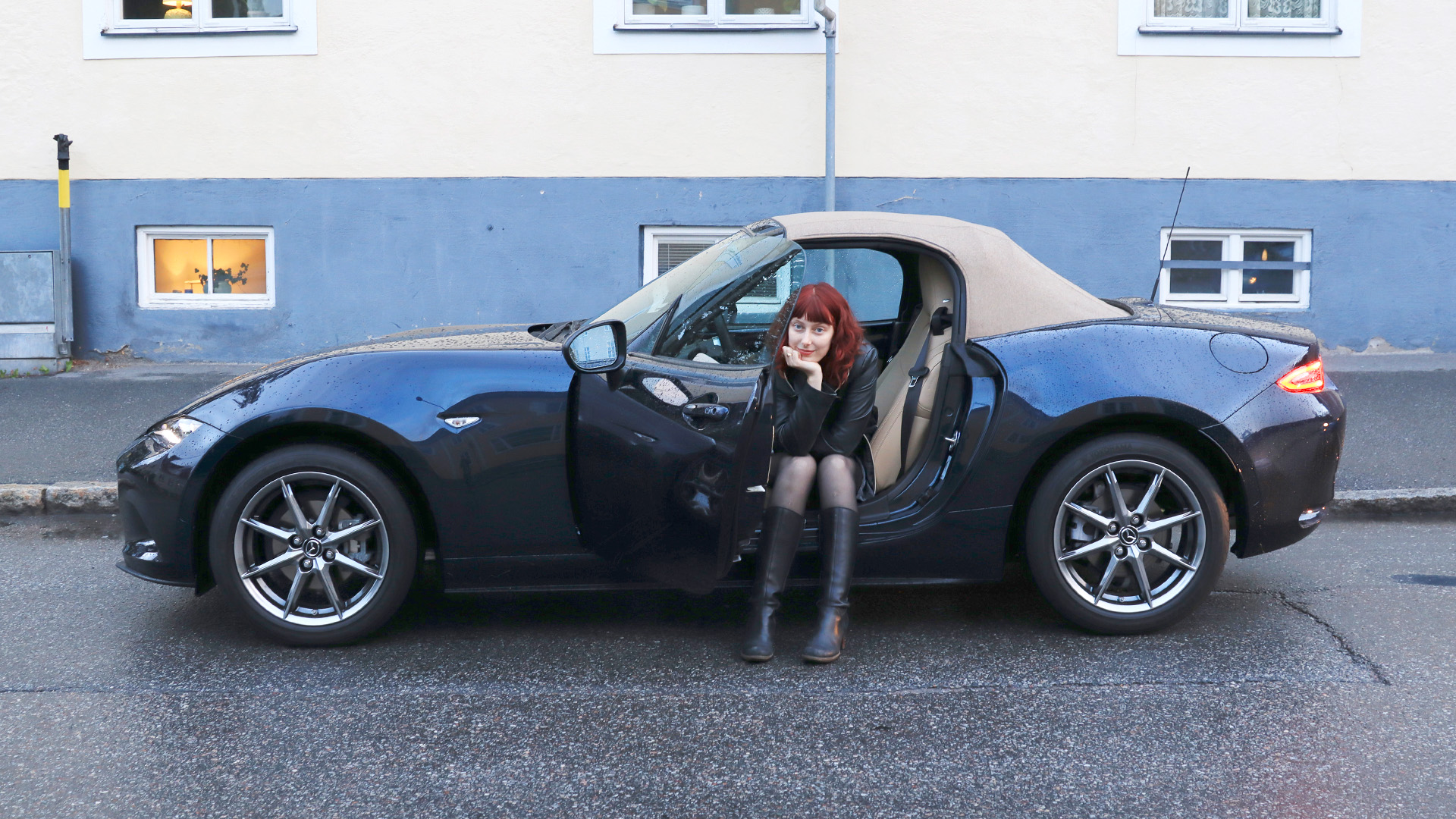 Hanna Brante framför en mörkblå Mazda Miata MX-5.