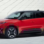 Röd Nissan Micra, ny generation, parkerad i urban miljö. Provkörning av elbilen