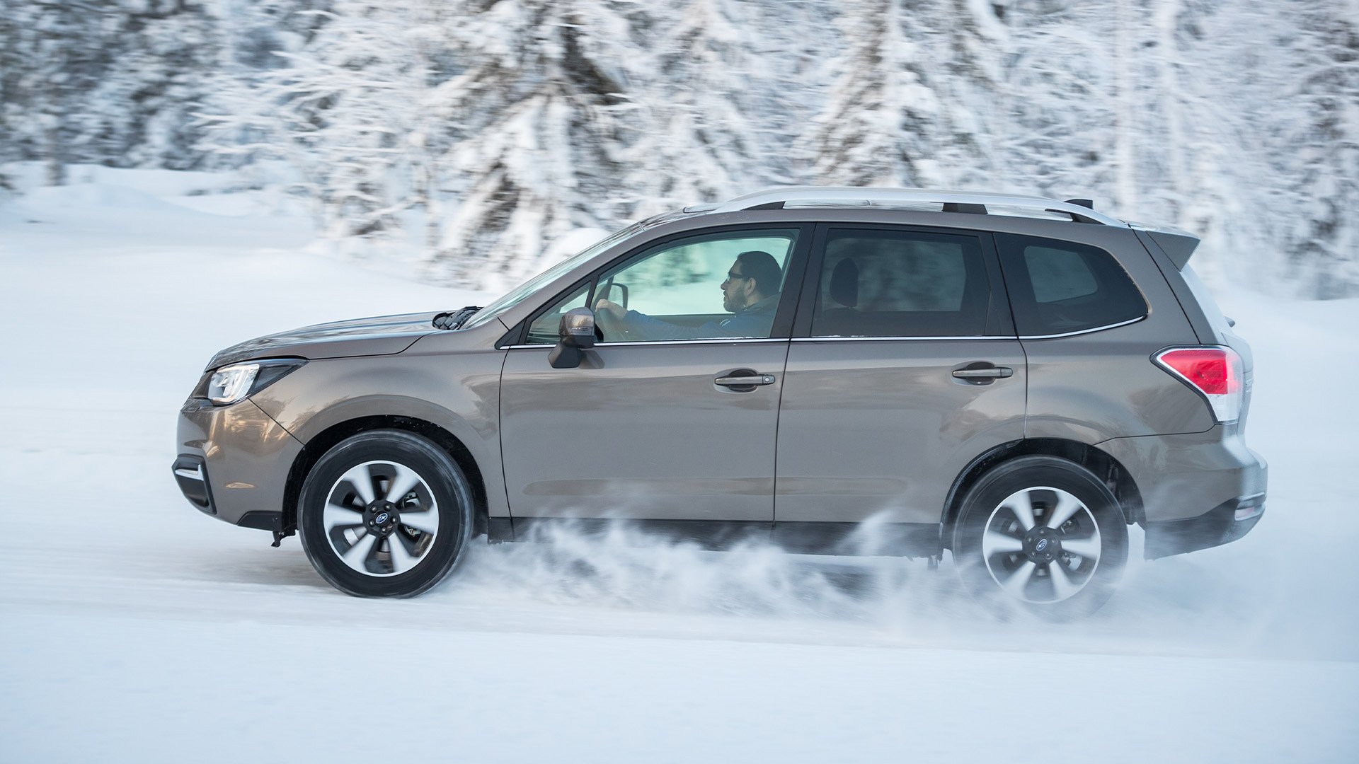 Grå Subaru Forester i profil kör i snö.