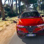 Röd Alfa Romeo Tonale på landsväg fotad framifrån.