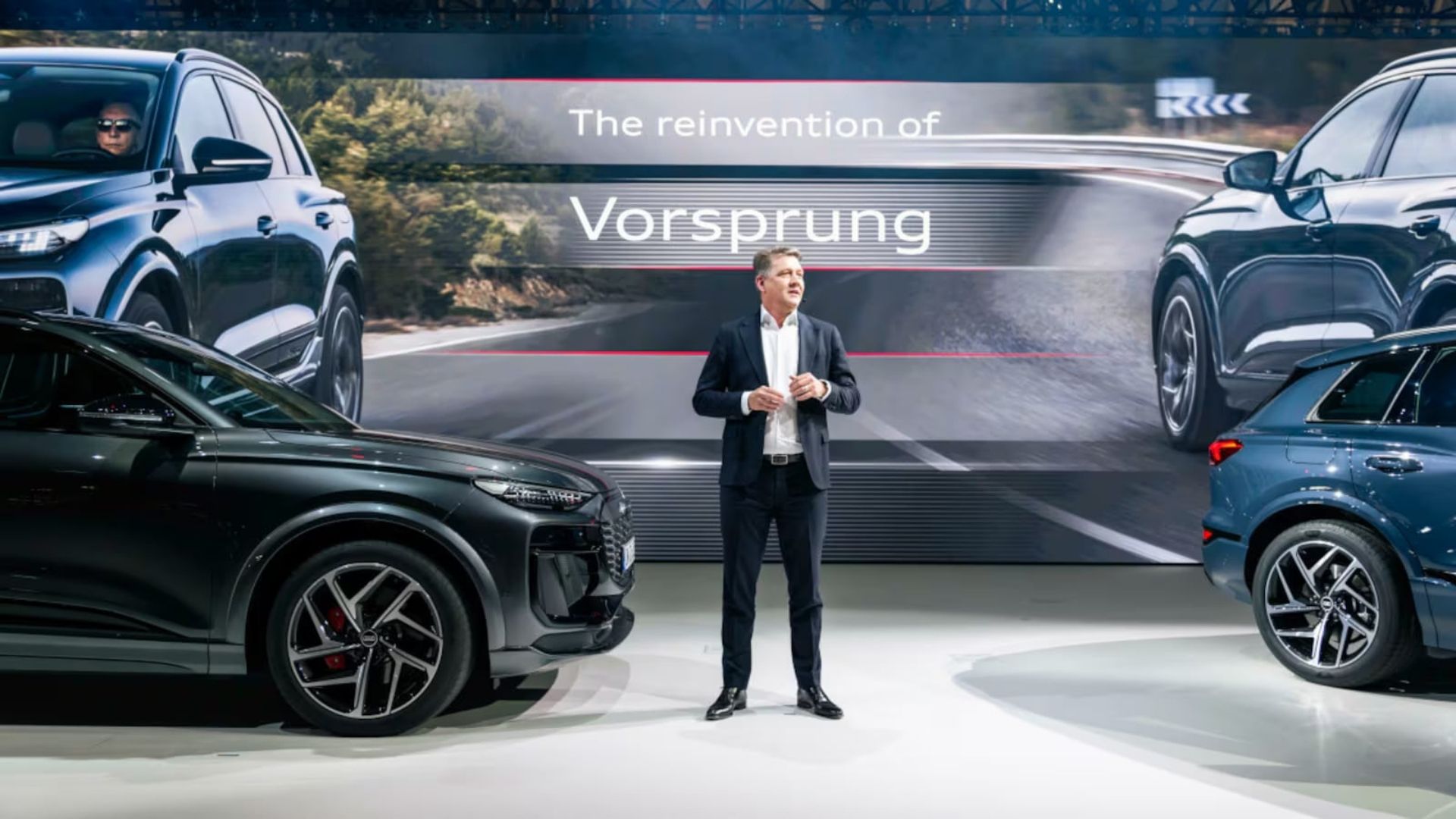 Audi-chef Gernot Döllner står på scen mellan två SUV-modeller under presentation
