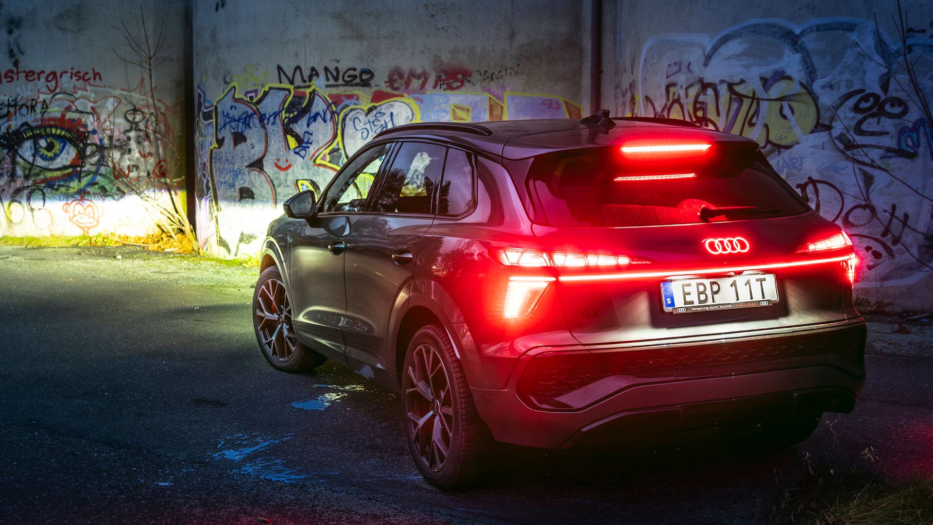 Audi Q3 e-hybrid sedd bakifrån med graffitivägg i bakgrunden.