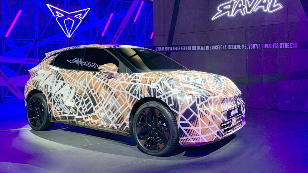 Kamouflerad Cupra Raval snett från sidan i studiomiljö. 