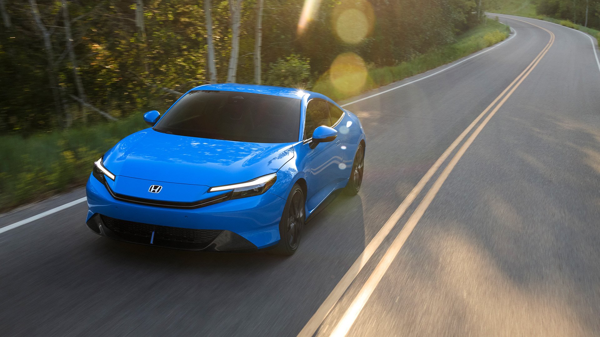 Racingblå Honda Prelude snett framifrån kör på landsväg.