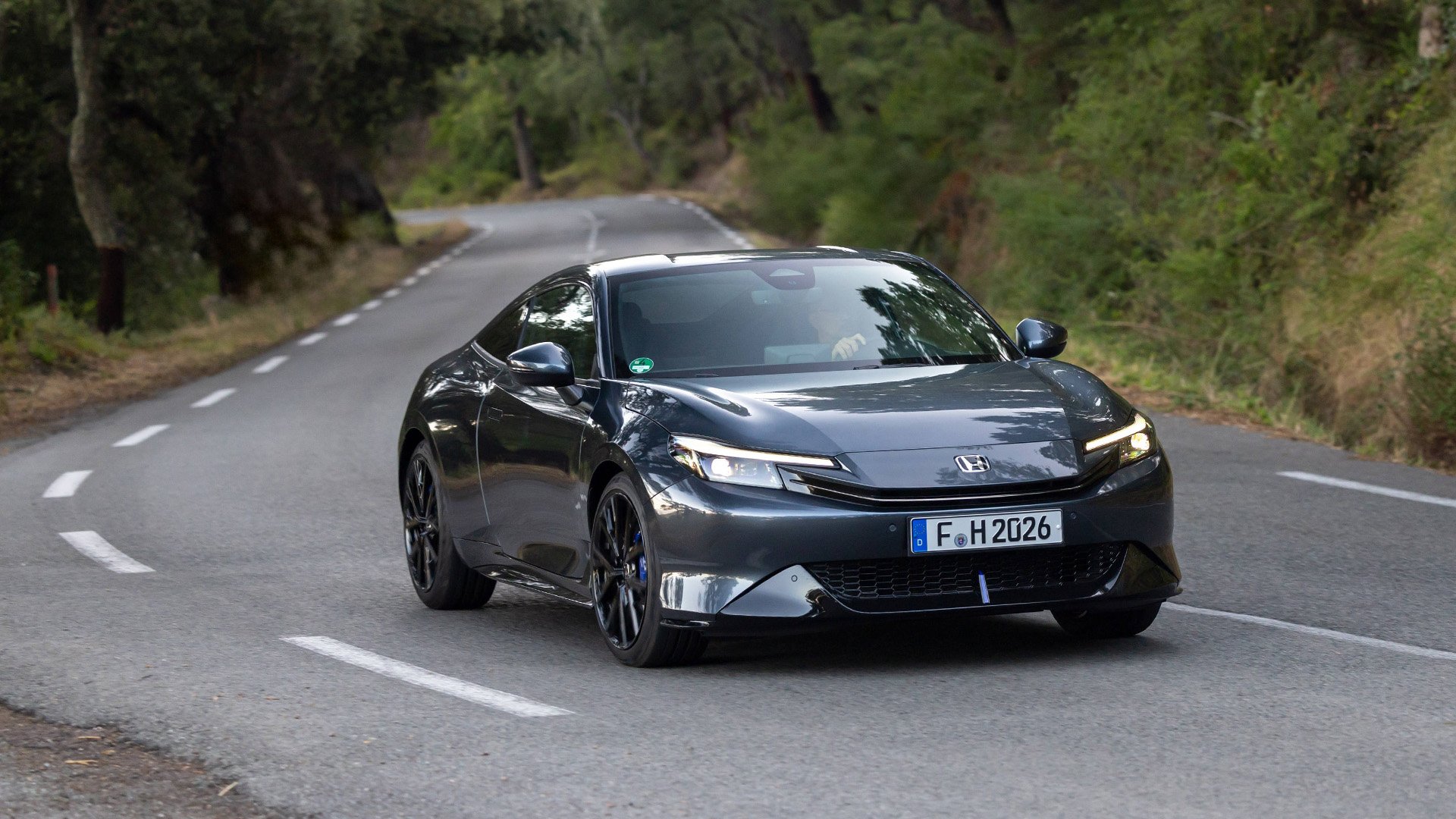 Grå Honda Prelude snett framifrån kör på landsväg.