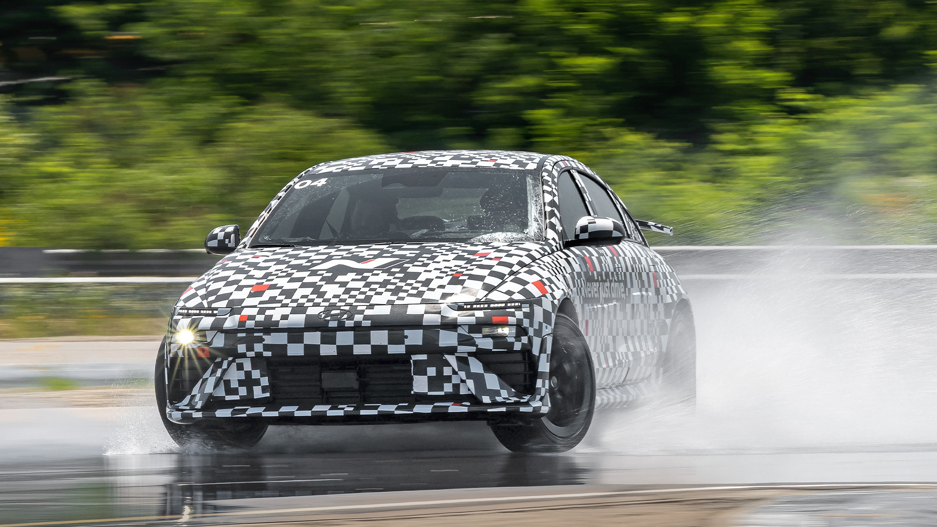 Kamouflerad Hyundai Ioniq 6 N kanar på vatten.