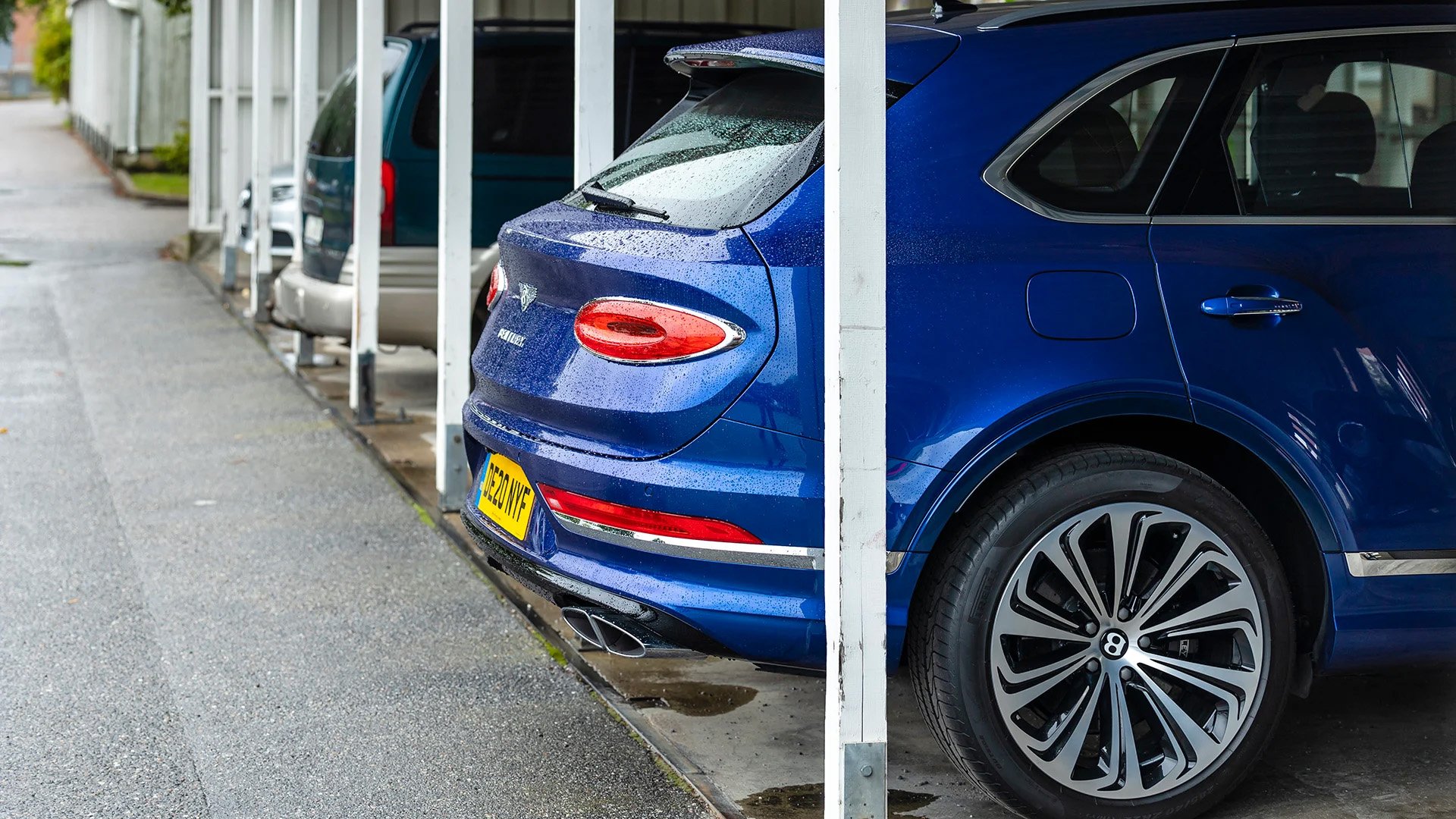 Stor blå suv parkerad i carport.