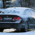 Kvinna skrapar bilrutor på vintern