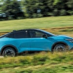 Ljusblå Nissan Leaf i profil kör på landsväg.