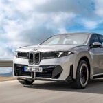 Grå BMW iX3 Neue Klasse på väg snett framifrån.
