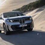 Grå BMW iX3 Neue Klasse på väg snett framifrån.