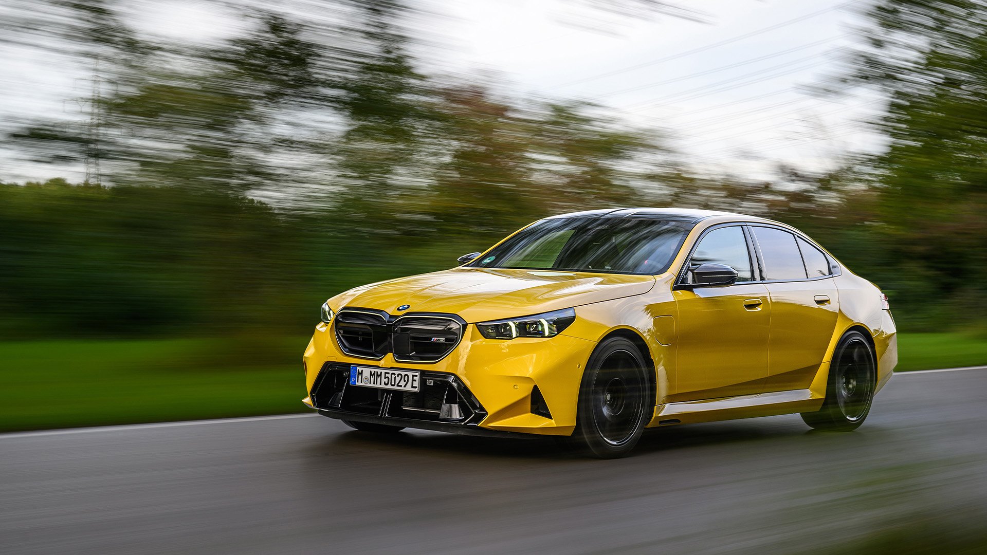 Gul BMW M5 på landsväg.