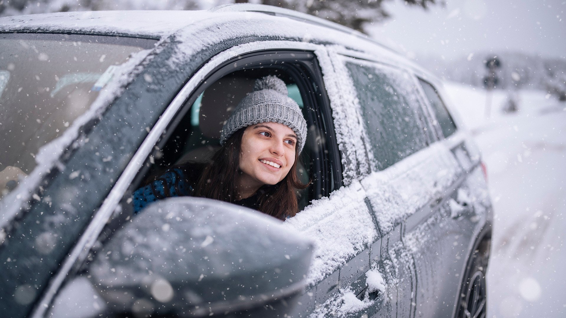 Tjej tittar ut ur snöig bil