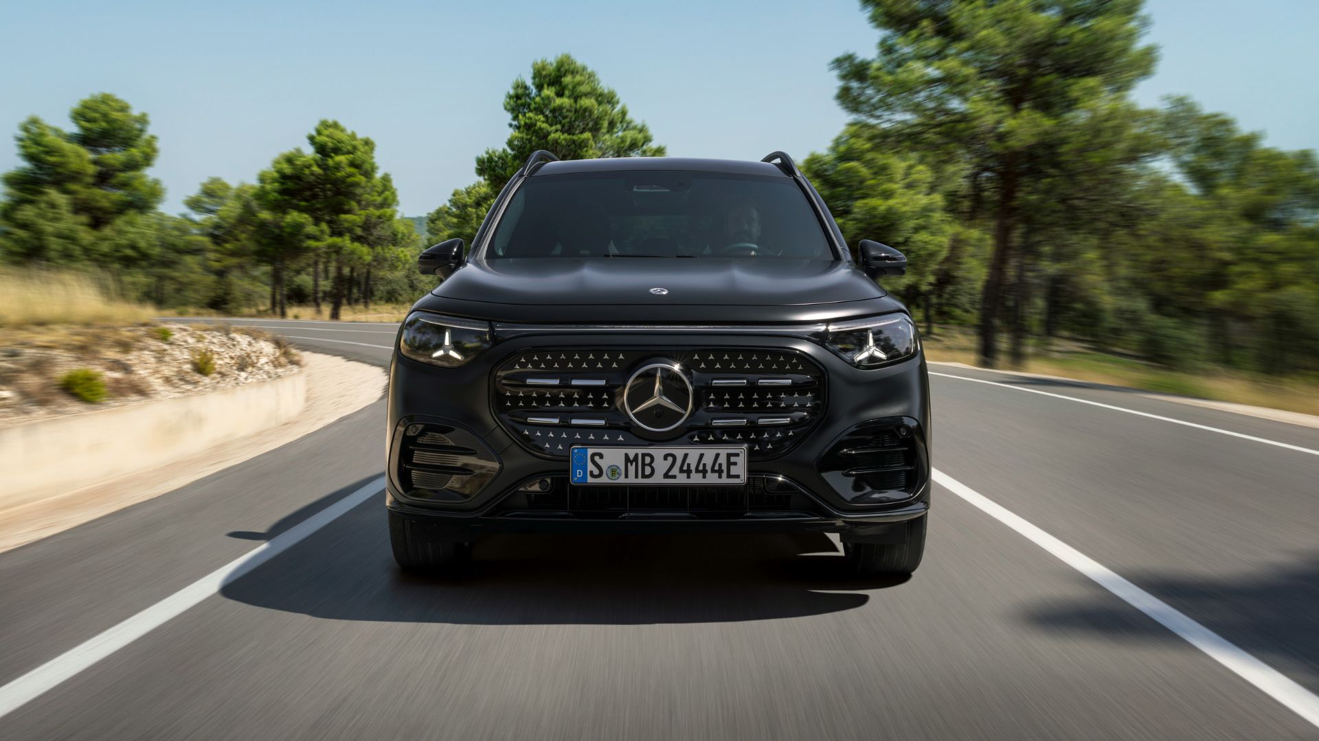 Eldrivna Mercedes GLB kör på landsväg i soligt landskap