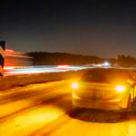 Elbil med varningsblinkers intill motorvägen