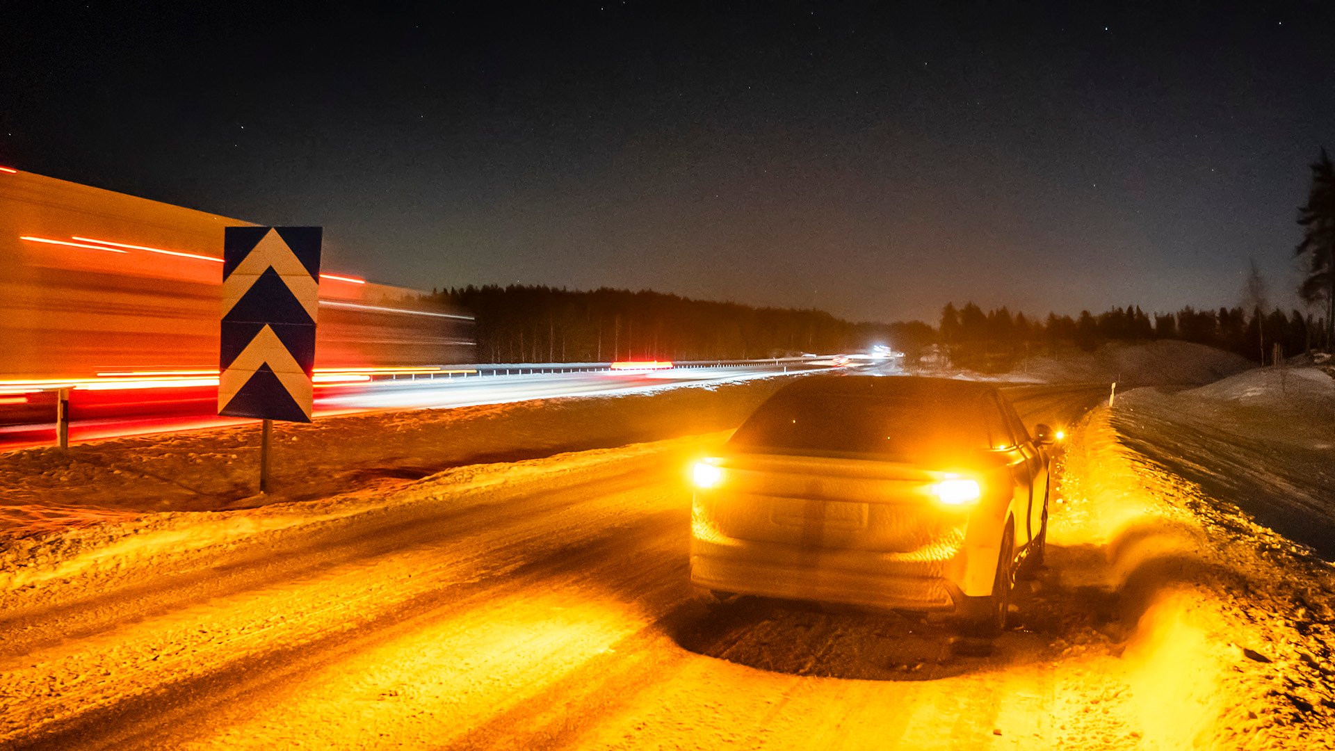 Elbil med varningsblinkers intill motorvägen
