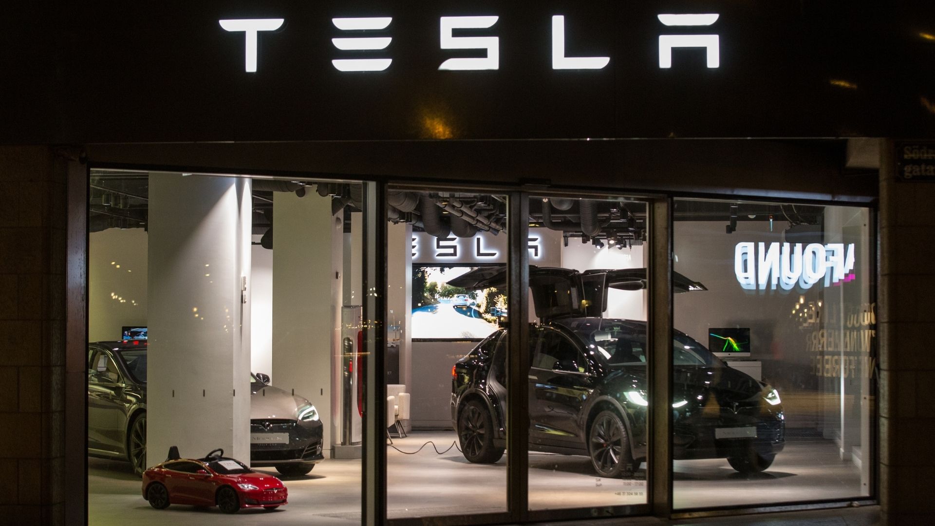 esla-showroom med flera bilar upplysta bakom glasfasad