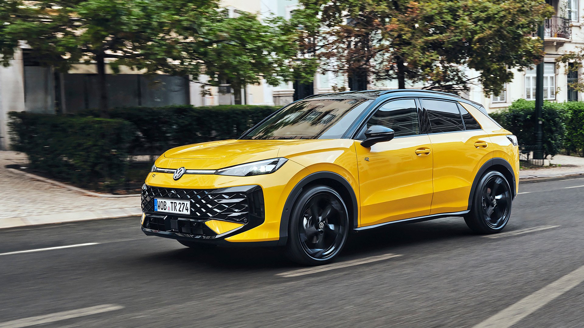 Gul Volkswagen T-Roc snett från sidan på väg i stadsmiljö.