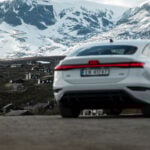Vit Audi A6 e-tron med snötäckta berg i bakgrunden.