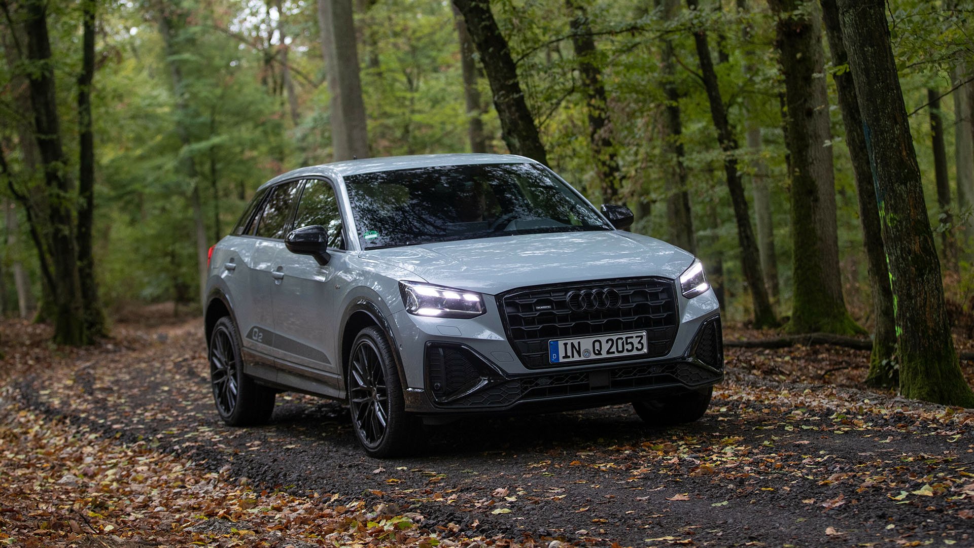 Grå Audi Q2 på skogsväg snett framifrån.