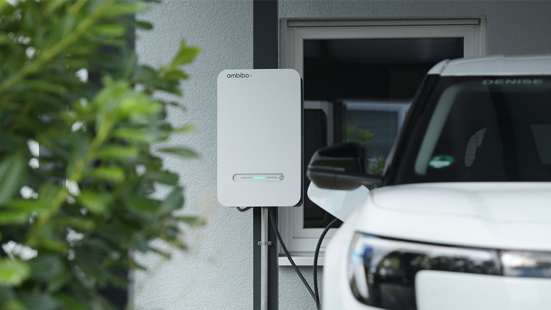 Laddbox för dubbelriktad laddning installerad vid villa med elbil parkerad utanför